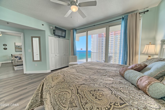 bedroom with a textured ceiling, access to outside, dark hardwood / wood-style floors, a closet, and ceiling fan