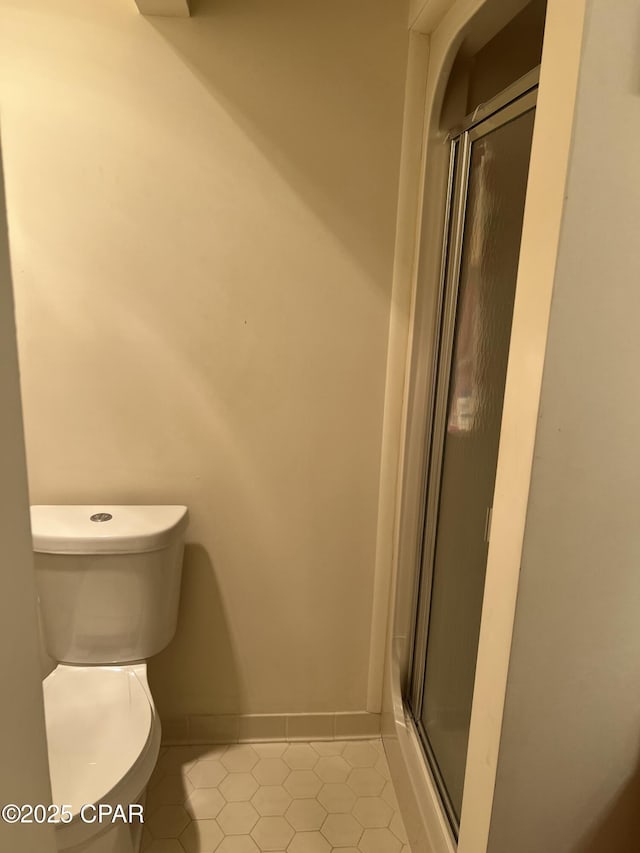 bathroom with a shower with door, tile patterned floors, and toilet