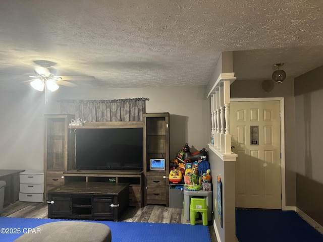 living room featuring ceiling fan, dark wood-type flooring, and a textured ceiling