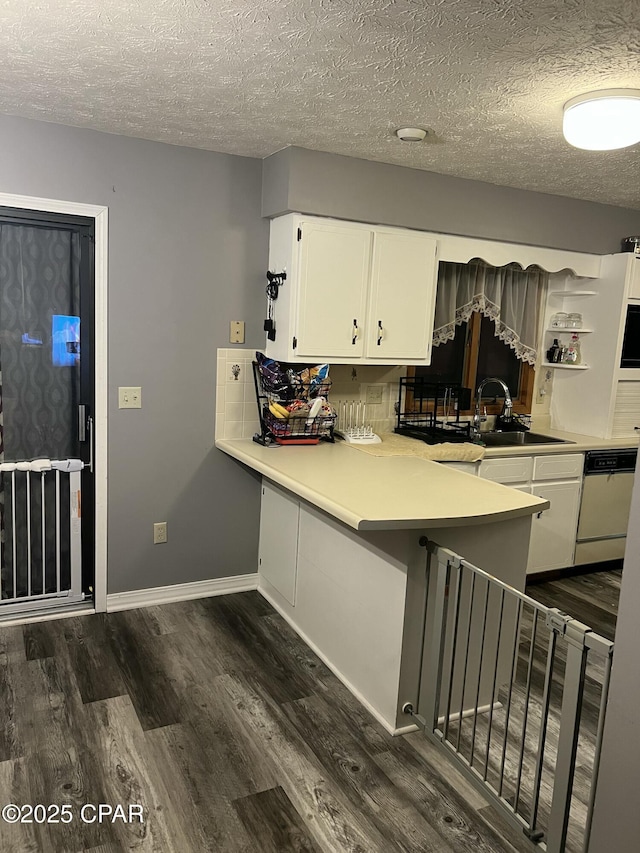 kitchen featuring sink, white cabinets, white dishwasher, kitchen peninsula, and a textured ceiling