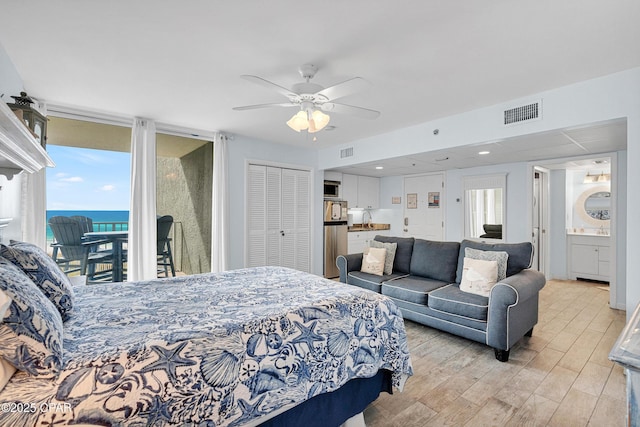 bedroom featuring ensuite bathroom, a water view, access to outside, a closet, and ceiling fan