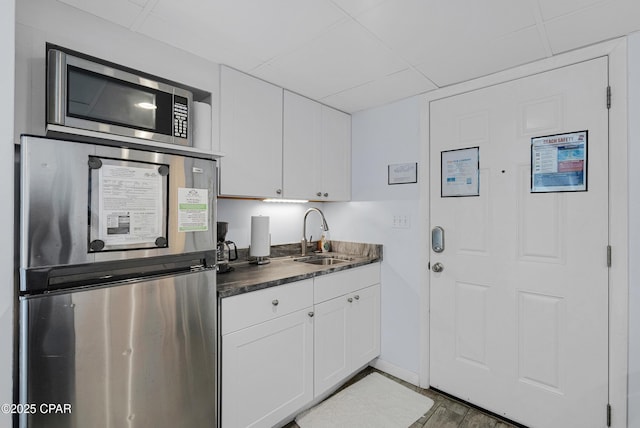 kitchen featuring white cabinetry, appliances with stainless steel finishes, sink, and a drop ceiling