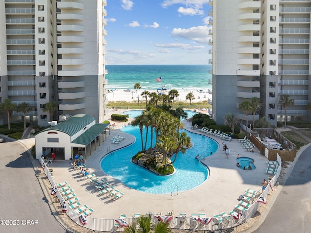 view of swimming pool with a water view and a beach view