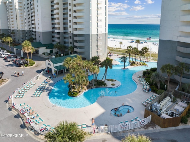 view of swimming pool with a water view and a beach view