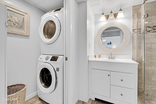 laundry area with stacked washer / dryer, sink, and light wood-type flooring