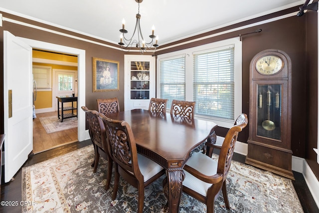 dining space with ornamental molding, dark wood-type flooring, a notable chandelier, and built in shelves