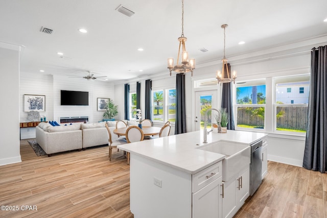 kitchen with sink, decorative light fixtures, dishwasher, a kitchen island with sink, and white cabinets