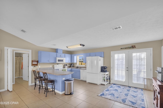 kitchen featuring white appliances, a breakfast bar area, blue cabinetry, and french doors