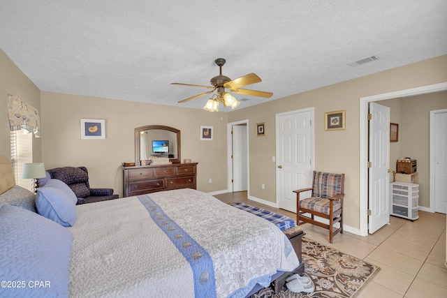 tiled bedroom with ceiling fan and a textured ceiling