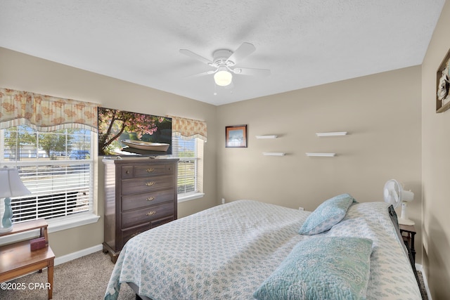 bedroom with ceiling fan, carpet, and a textured ceiling