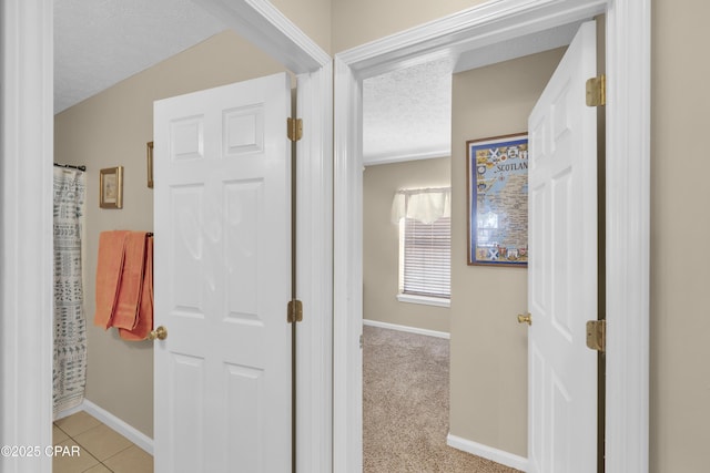 hallway featuring light tile patterned flooring and a textured ceiling