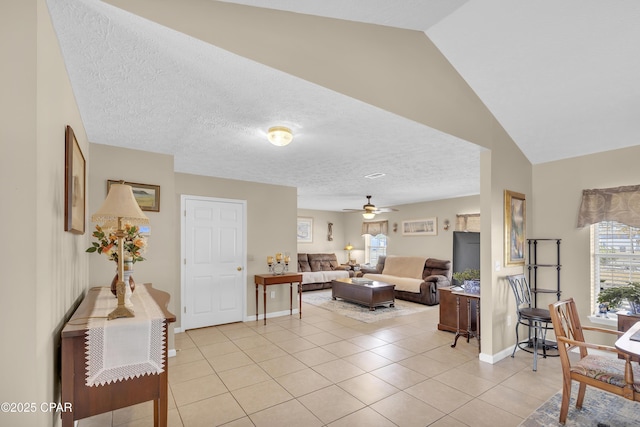 living room featuring light tile patterned flooring, ceiling fan, vaulted ceiling, and a textured ceiling