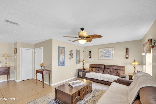 living room featuring ceiling fan, light tile patterned floors, and a textured ceiling