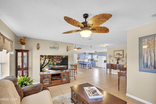 tiled living room with ceiling fan and a textured ceiling