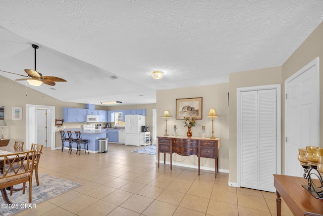 tiled dining room featuring ceiling fan, lofted ceiling, sink, and a textured ceiling