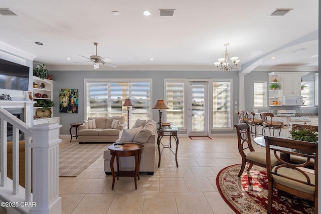 tiled living room with ceiling fan with notable chandelier, ornamental molding, decorative columns, and a healthy amount of sunlight