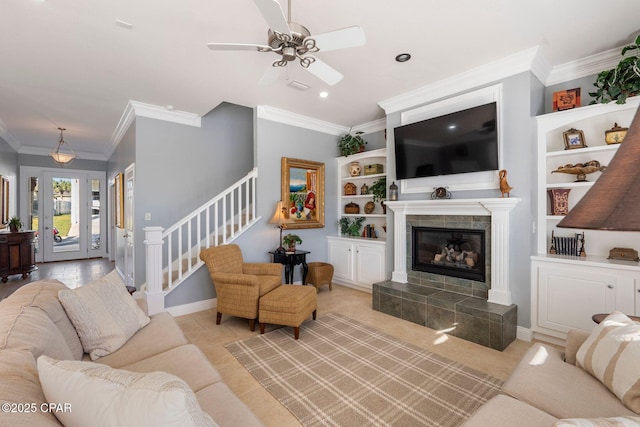 living room featuring ornamental molding, a tile fireplace, and ceiling fan