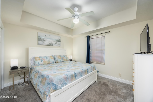 bedroom featuring dark carpet, a raised ceiling, and ceiling fan