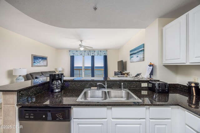 kitchen with sink, dishwasher, kitchen peninsula, white cabinets, and dark stone counters