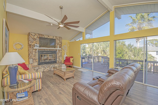 living room featuring a stone fireplace, wood-type flooring, high vaulted ceiling, and beamed ceiling