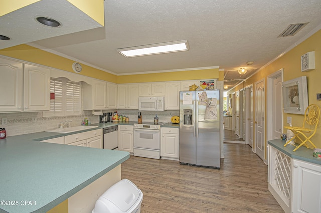 kitchen featuring sink, tasteful backsplash, ornamental molding, stainless steel appliances, and white cabinets