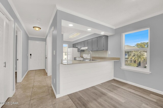 kitchen featuring gray cabinetry, tasteful backsplash, ornamental molding, kitchen peninsula, and white appliances