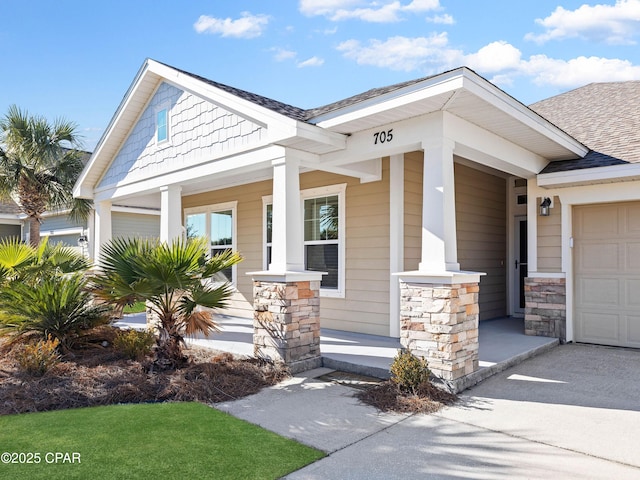 view of front of property with a garage, covered porch, stone siding, and roof with shingles