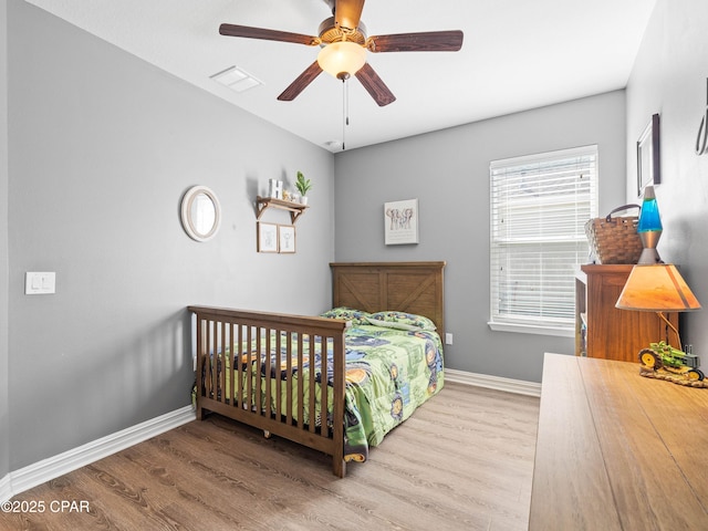bedroom featuring a ceiling fan, visible vents, baseboards, and wood finished floors