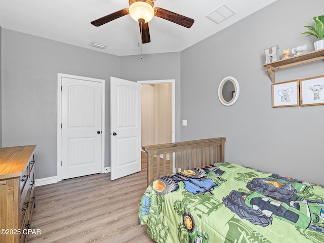 bedroom with light wood-style floors, baseboards, visible vents, and a ceiling fan