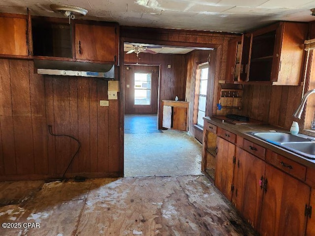 kitchen featuring ceiling fan, sink, and wood walls