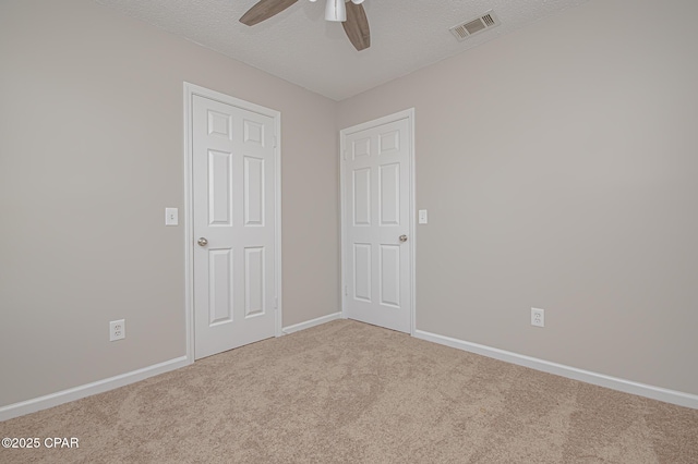 empty room featuring ceiling fan, carpet flooring, and a textured ceiling