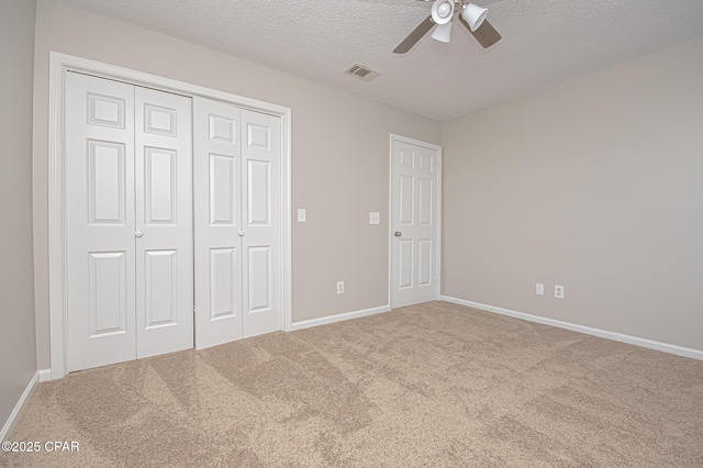 unfurnished bedroom with ceiling fan, a closet, a textured ceiling, and carpet