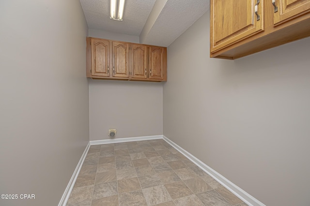 laundry room with cabinets, electric dryer hookup, and a textured ceiling