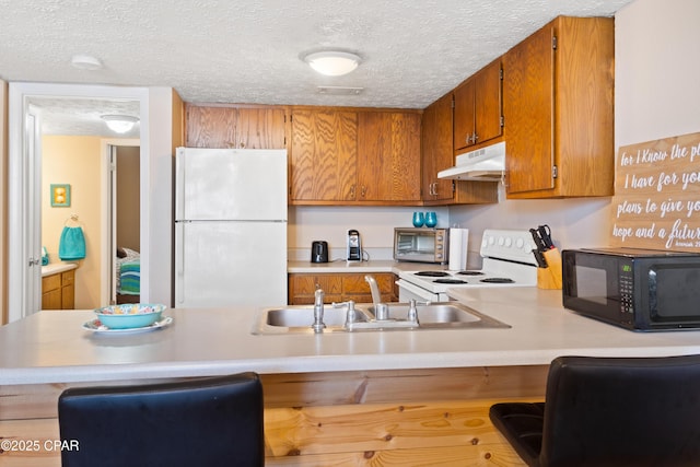 kitchen with a kitchen bar, sink, a textured ceiling, kitchen peninsula, and white appliances