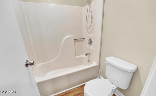 bathroom featuring hardwood / wood-style flooring, shower / tub combination, and toilet