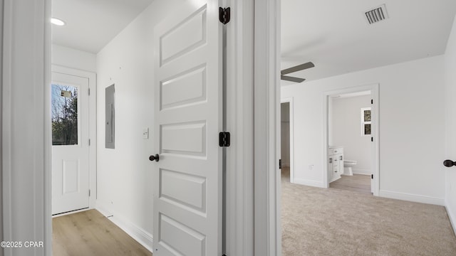 corridor featuring light carpet and electric panel