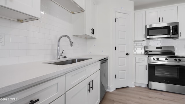 kitchen with white cabinetry, appliances with stainless steel finishes, sink, and light hardwood / wood-style flooring