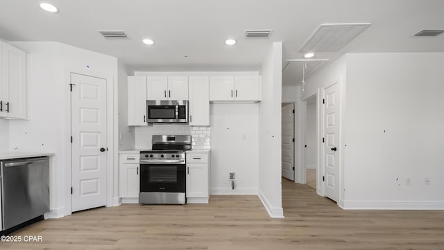 kitchen with white cabinetry, decorative backsplash, stainless steel appliances, and light hardwood / wood-style flooring