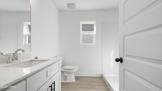 bathroom with vanity, toilet, hardwood / wood-style floors, and a shower