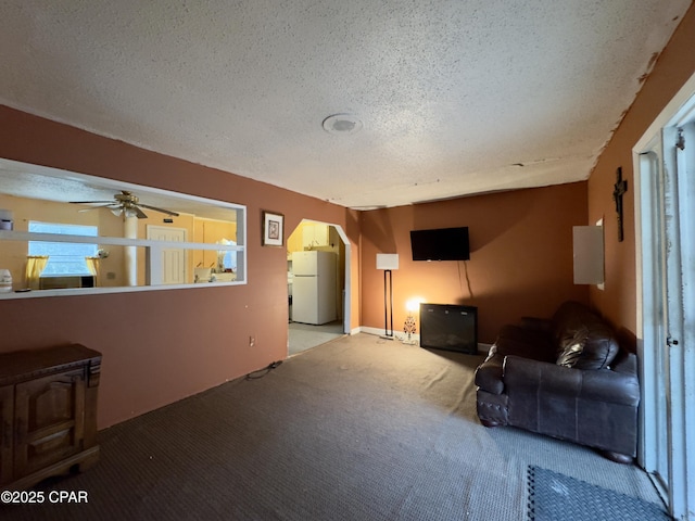 carpeted living room featuring ceiling fan and a textured ceiling