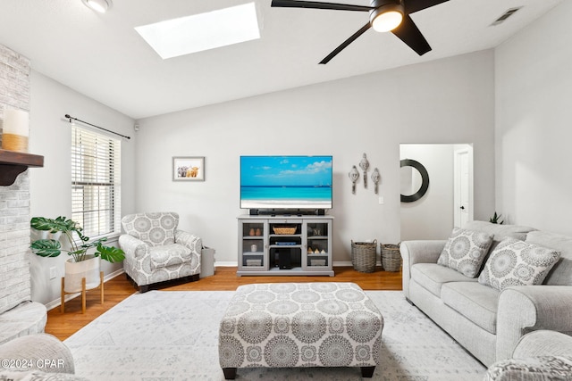 living room with wood-type flooring, lofted ceiling with skylight, and ceiling fan