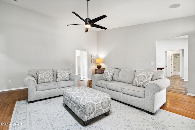 living room featuring ceiling fan, wood-type flooring, and a high ceiling