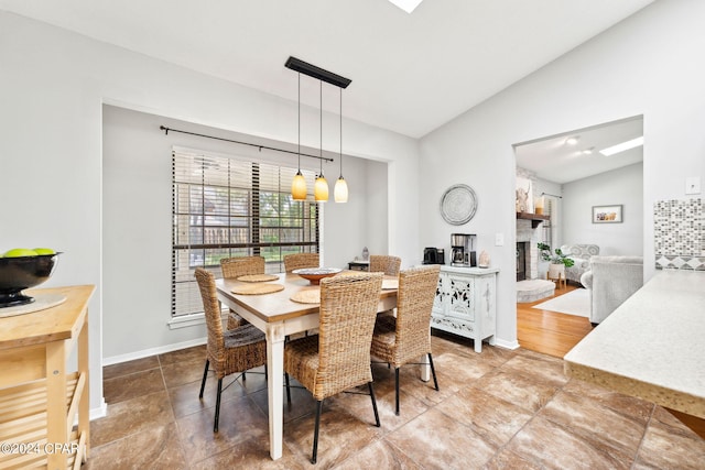 dining area with a brick fireplace and vaulted ceiling