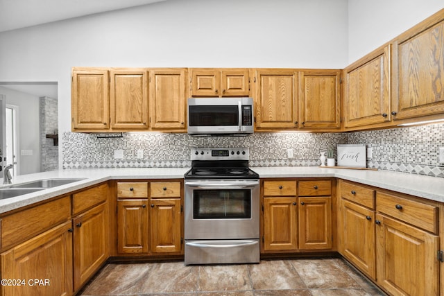 kitchen featuring stainless steel appliances, lofted ceiling, sink, and decorative backsplash