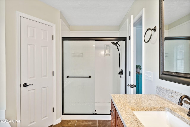 bathroom with vanity, tile patterned floors, a shower with door, and a textured ceiling