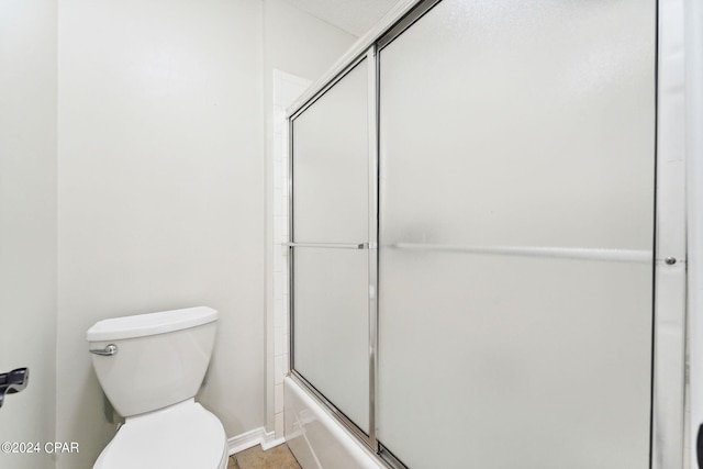 bathroom with bath / shower combo with glass door and toilet