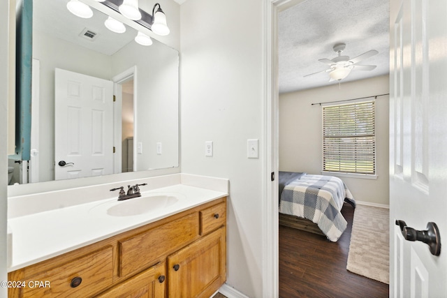 bathroom featuring hardwood / wood-style flooring, ceiling fan, vanity, a textured ceiling, and toilet