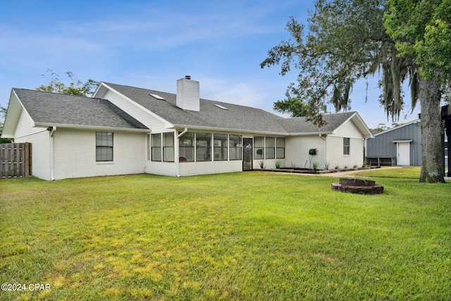 back of house with a fire pit, a sunroom, and a lawn