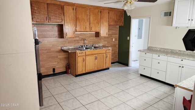 kitchen featuring light tile patterned flooring, sink, white cabinets, ceiling fan, and backsplash