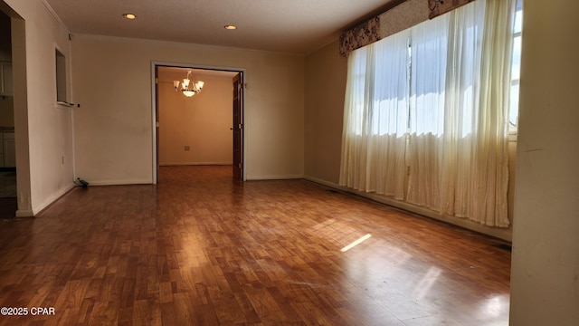 empty room featuring wood-type flooring and a chandelier